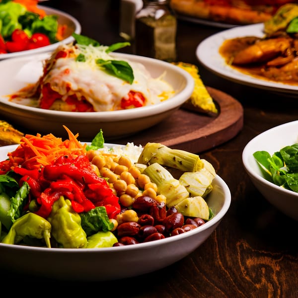 A table laden with various Italian dishes, including salads, lasagna, and a main course.